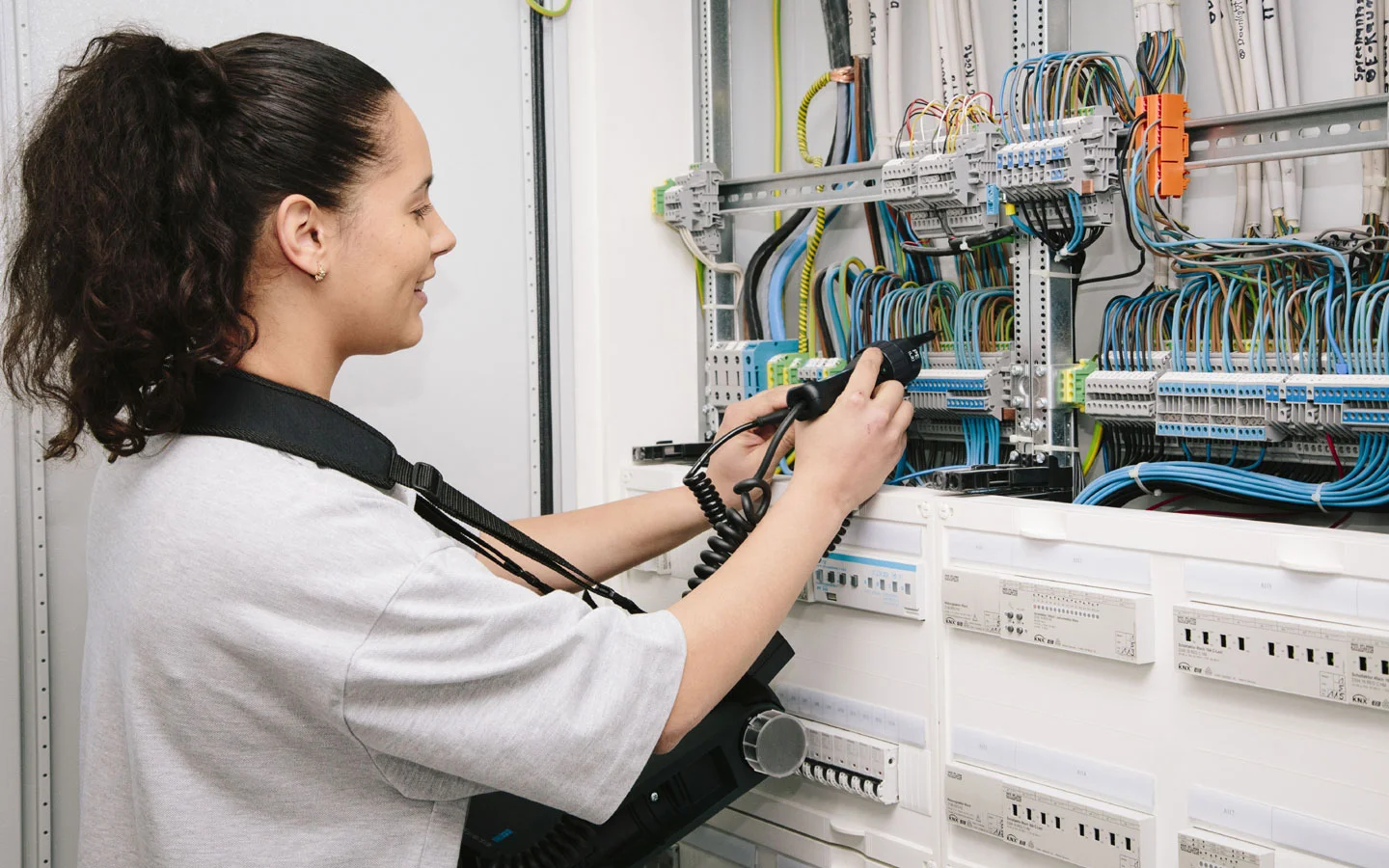 E-CHECK - Mitarbeiterin prüft im Schaltschrank mit einem Meßgerät · B+B Mess- und Sicherheitstechnik